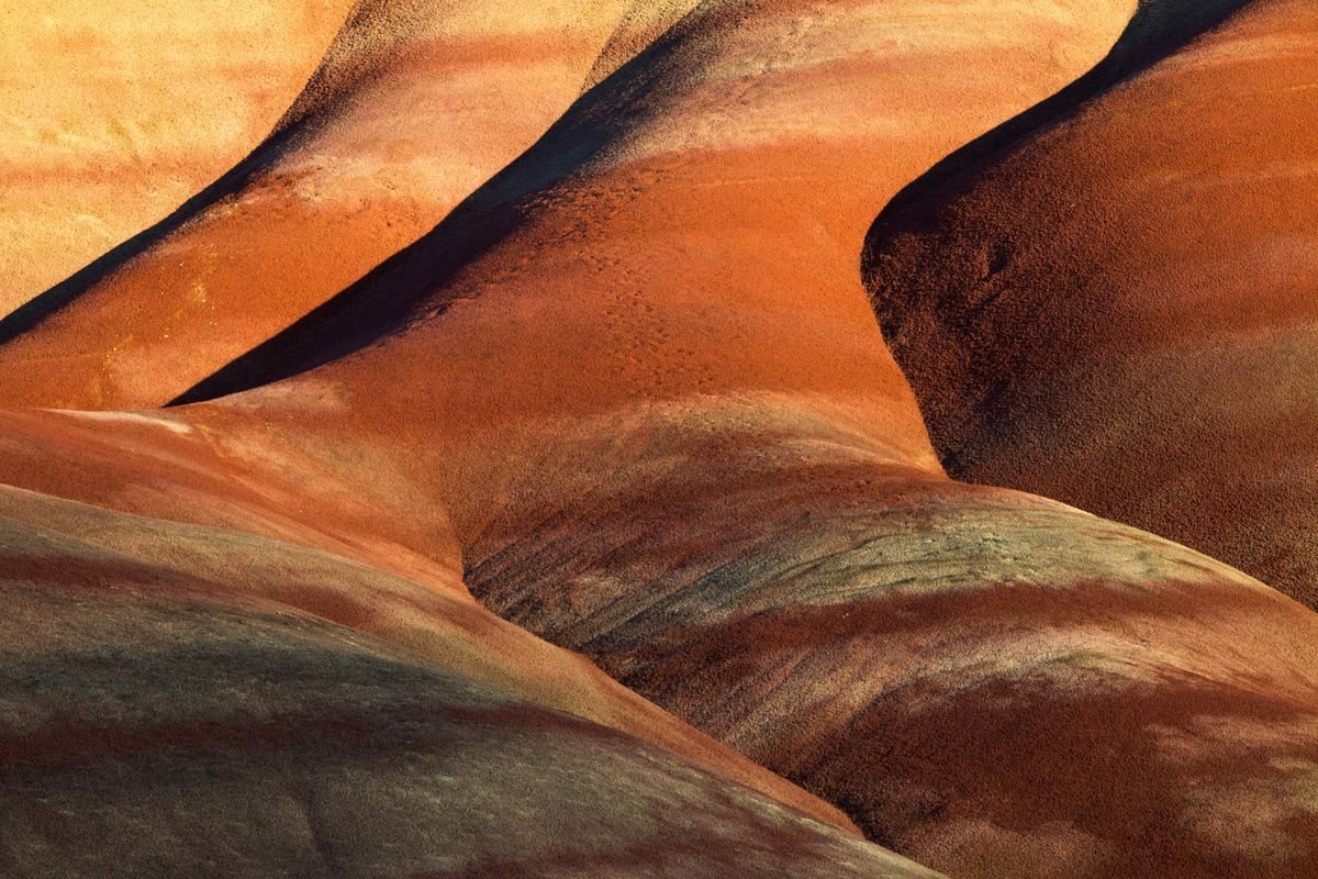 Layered rock in terracotta and ochre, light raking across it.