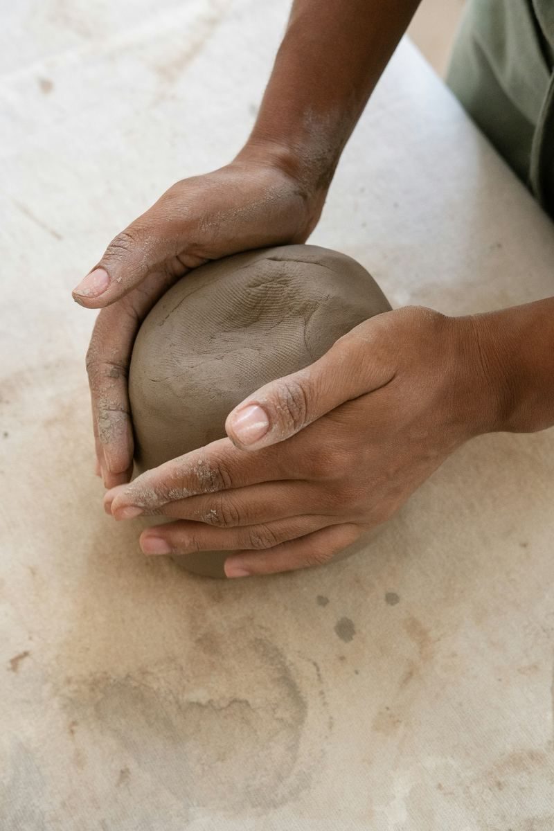 Two hands holding a ball of raw clay.
