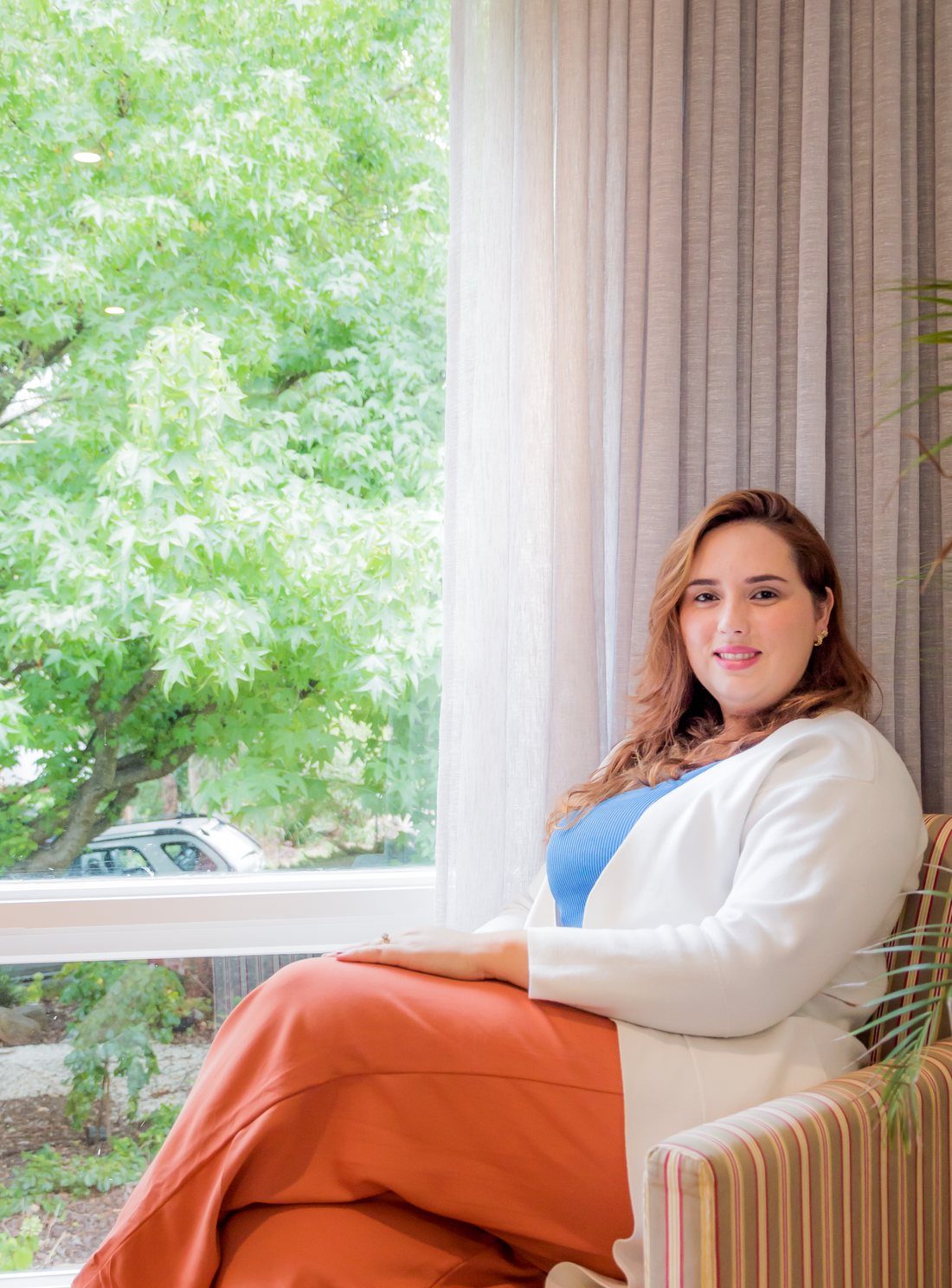 Etienny Trindade standing in a bright space, windows behind her.