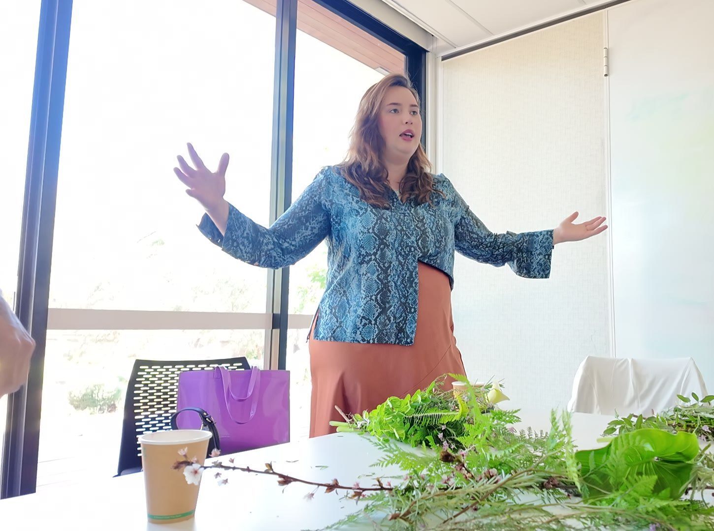 Etienny Trindade speaking to a group, hands open, daylight behind her.