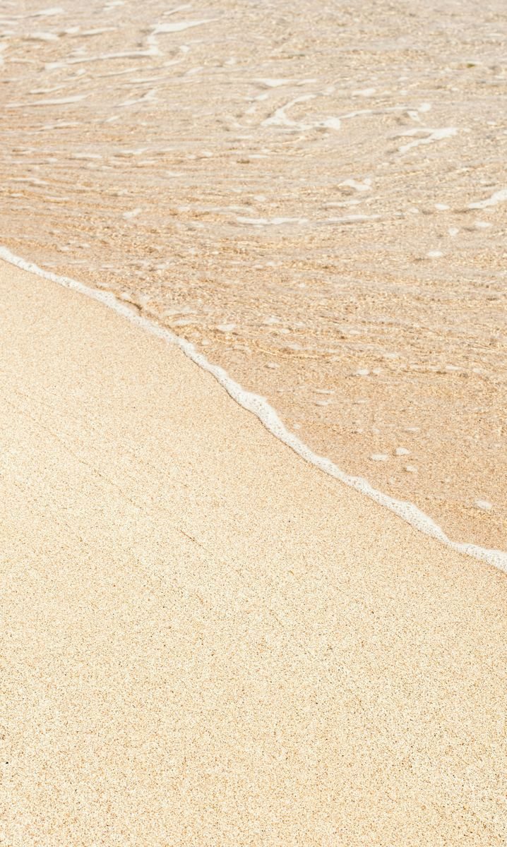 Shoreline at low light, the water drawing back over wet sand.